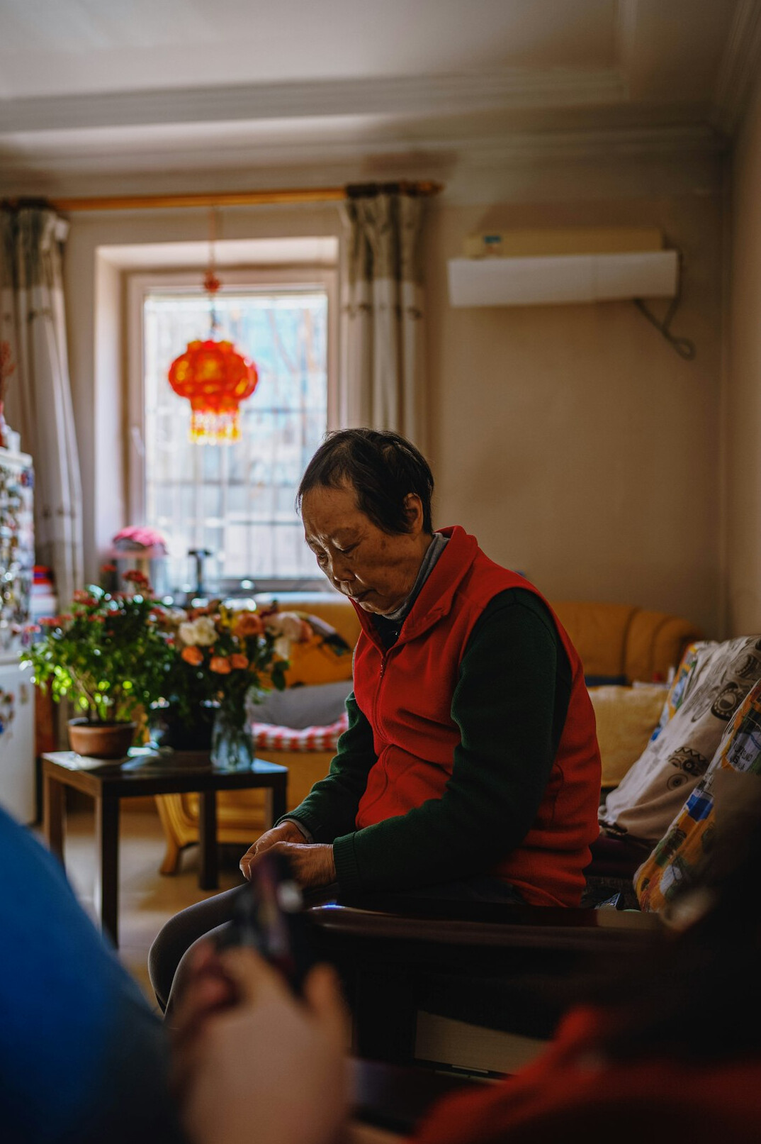 Photographer sitting and talking with an elderly woman in her home during an interview